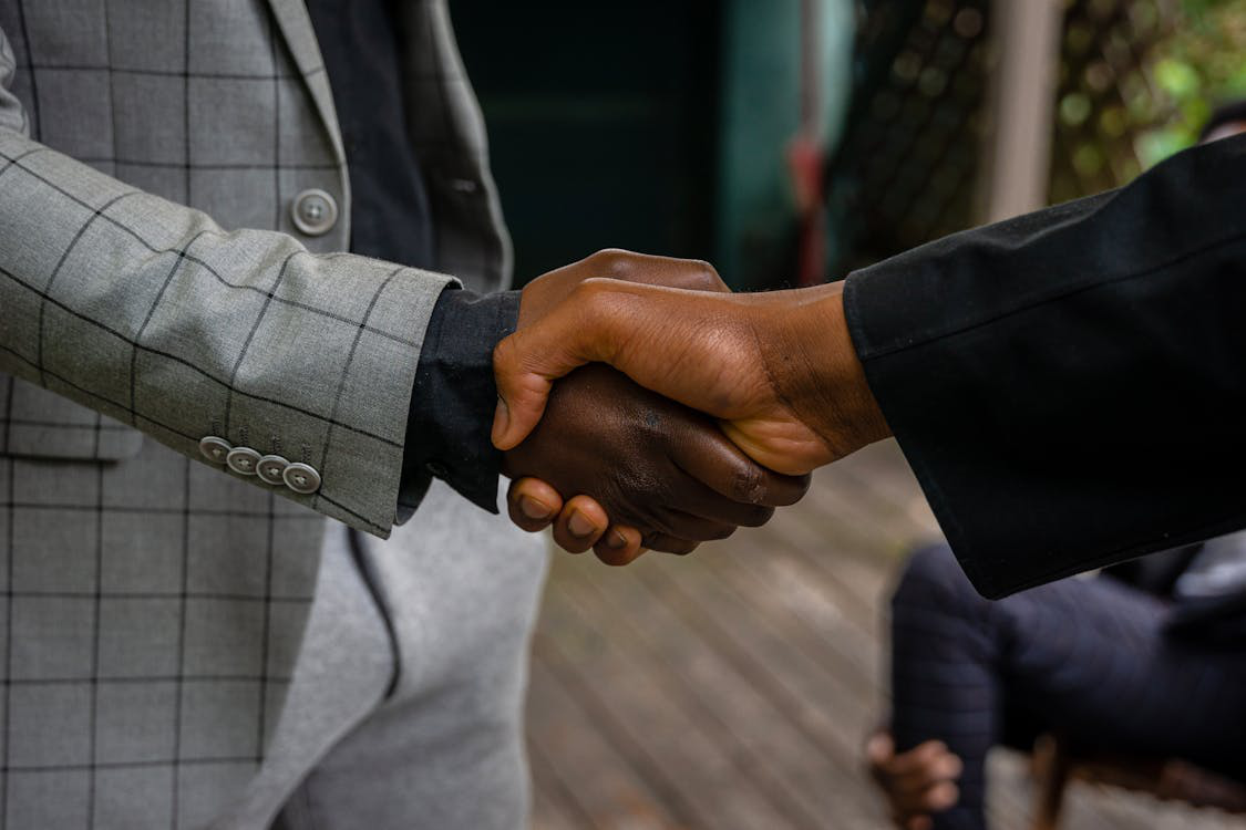 Two men in suit jackets shaking hands.
