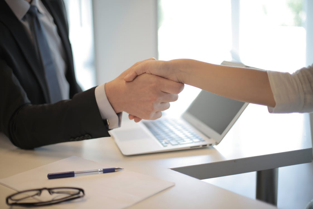 Person in a suit shaking hands with a new employee wearing a name tag