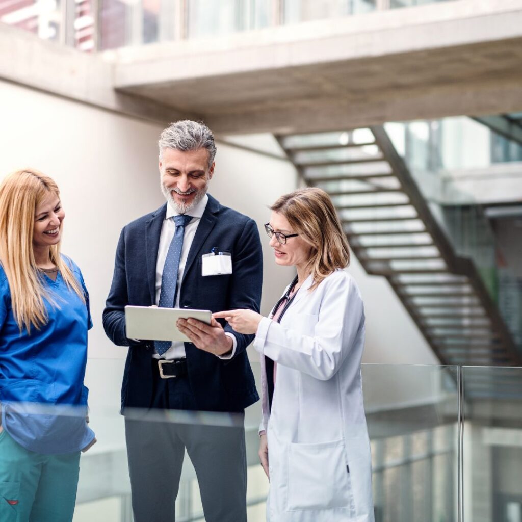 A healthcare team—doctor, administrator, and nurse—reviewing documents in a modern facility.