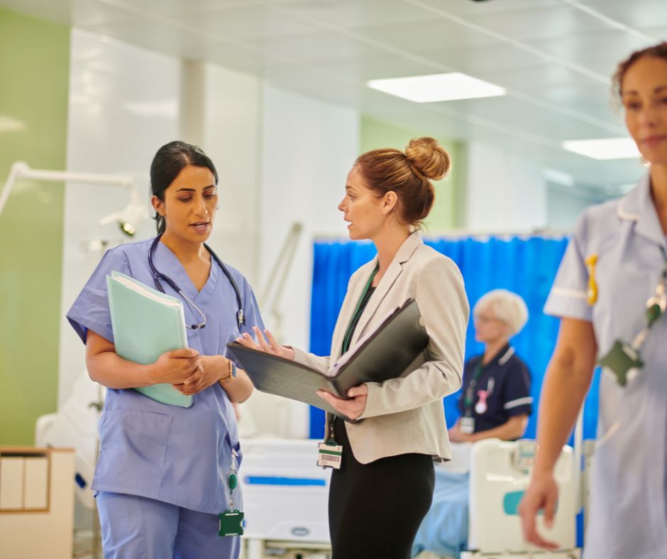 A nurse and a healthcare administrator discussing documents in a hospital ward.