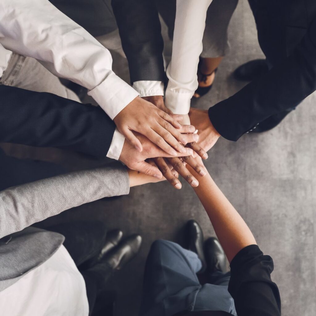 A diverse group of professionals stacking their hands together in a team-building gesture.