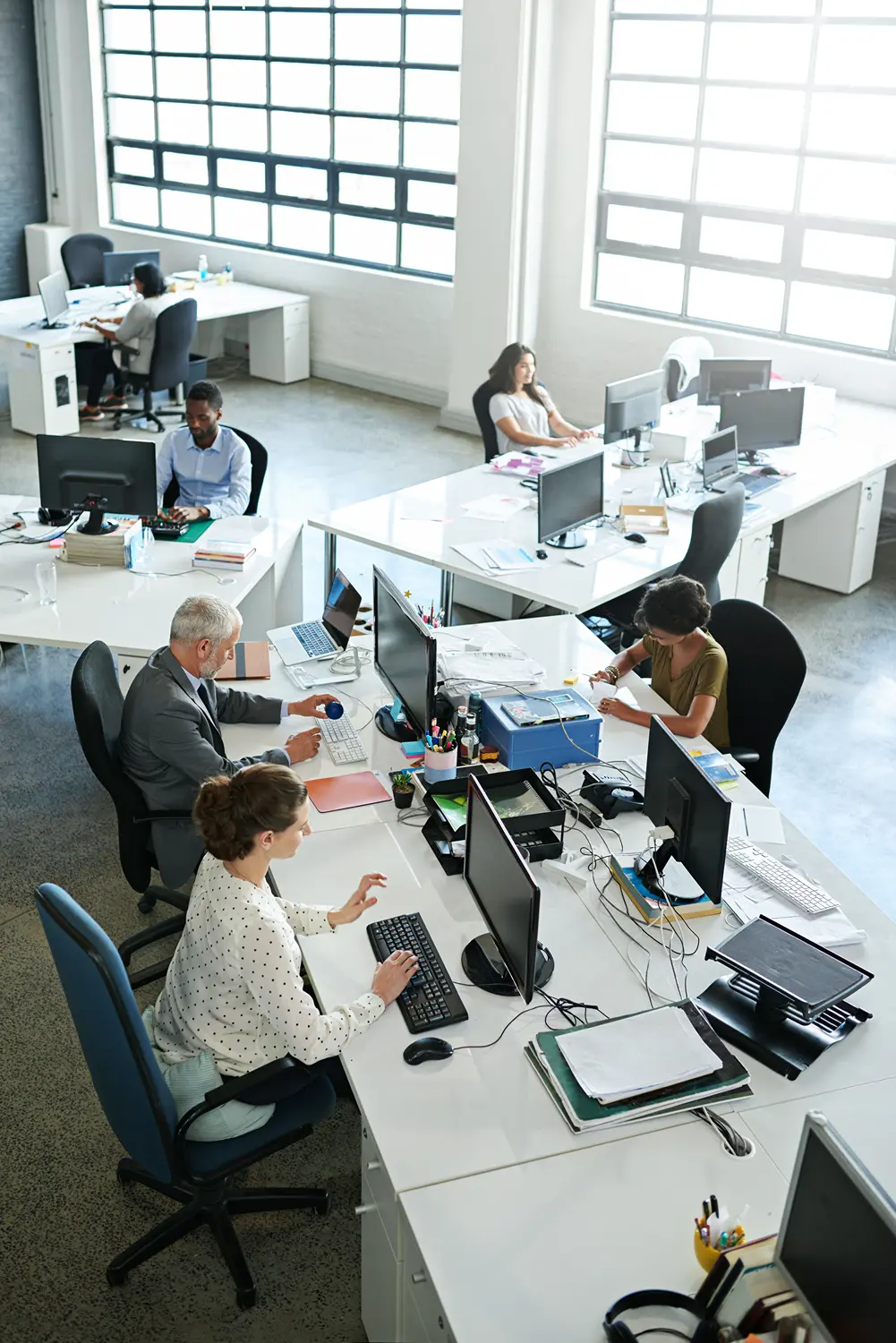 Busy open-plan office with employees working at desks and computers.
